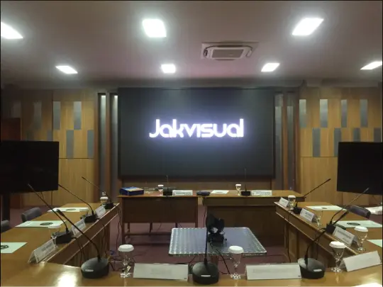 Layar ruang rapat menampilkan presentasi dengan lampu ruangan menyala